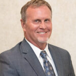 Here's an alt tag for the image: `Headshot of a man in a suit`