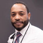 Here's an alt tag for the image: Headshot of a man in a white shirt and tie.