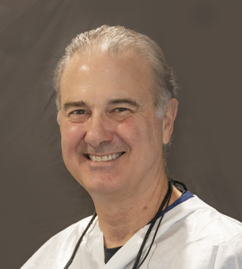 Here's an alt tag for the image: Smiling male doctor in scrubs.