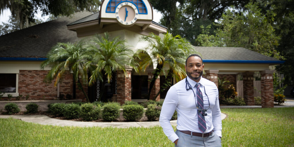 Smiling dentist standing outside his office.